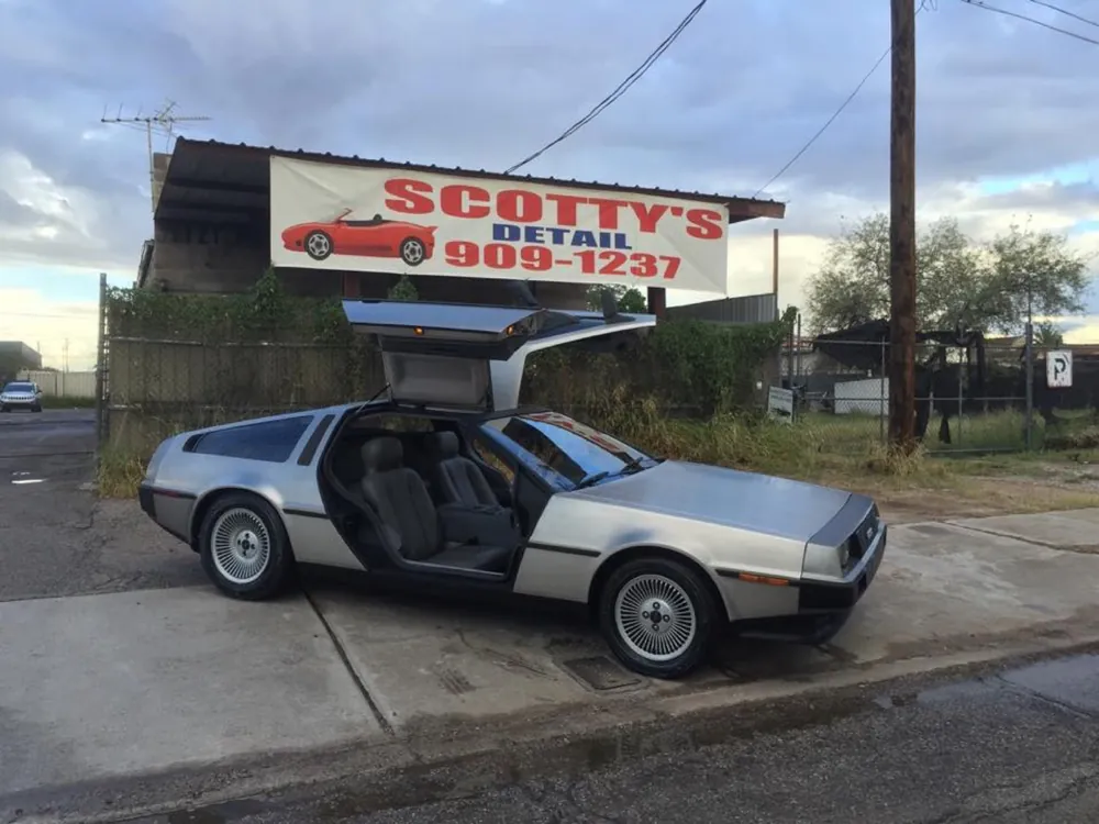 Silver DeLorean with its gullwing doors open at the shop