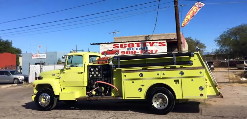 Vintage yellow fire engine parked under the Scotty's Detail banner