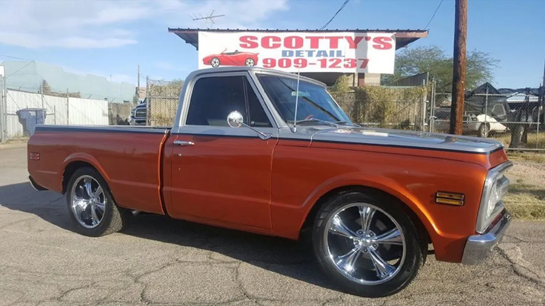 Classic pickup with chrome wheels parked under the Scotty's Detail banner